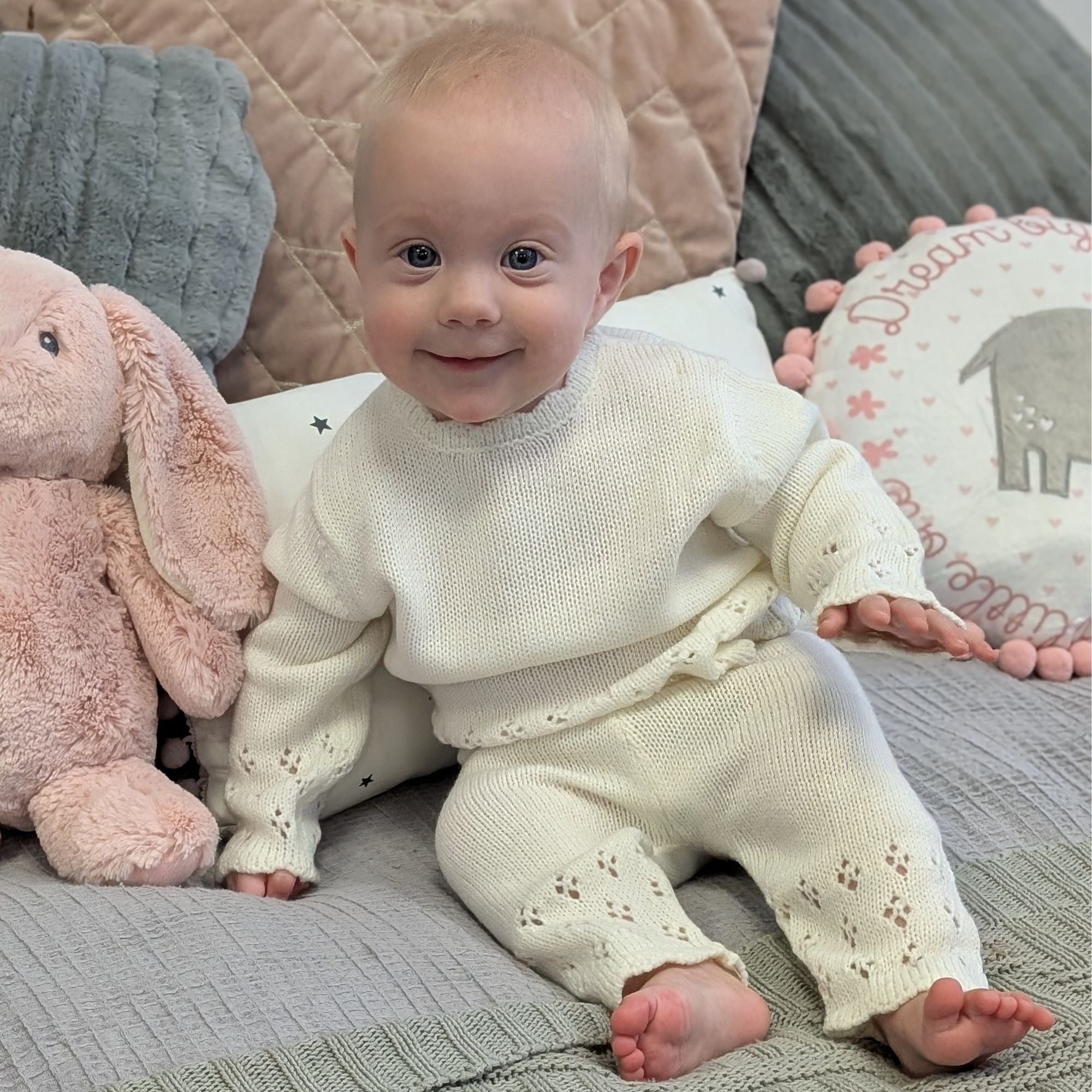 White baby clothes outfit worn by a smiling baby.