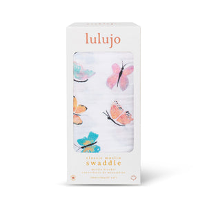 Large cotton muslin swaddle blanket featuring a delicate butterfly print in pinks and lilacs - shown in box. Lulujo.