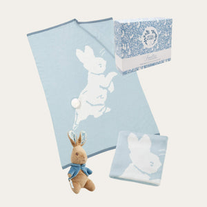 A soft blue knitted baby blanket with large peter rabbit design and a peter rabbit toy gift set presented in a box. Bumbles and Boo.