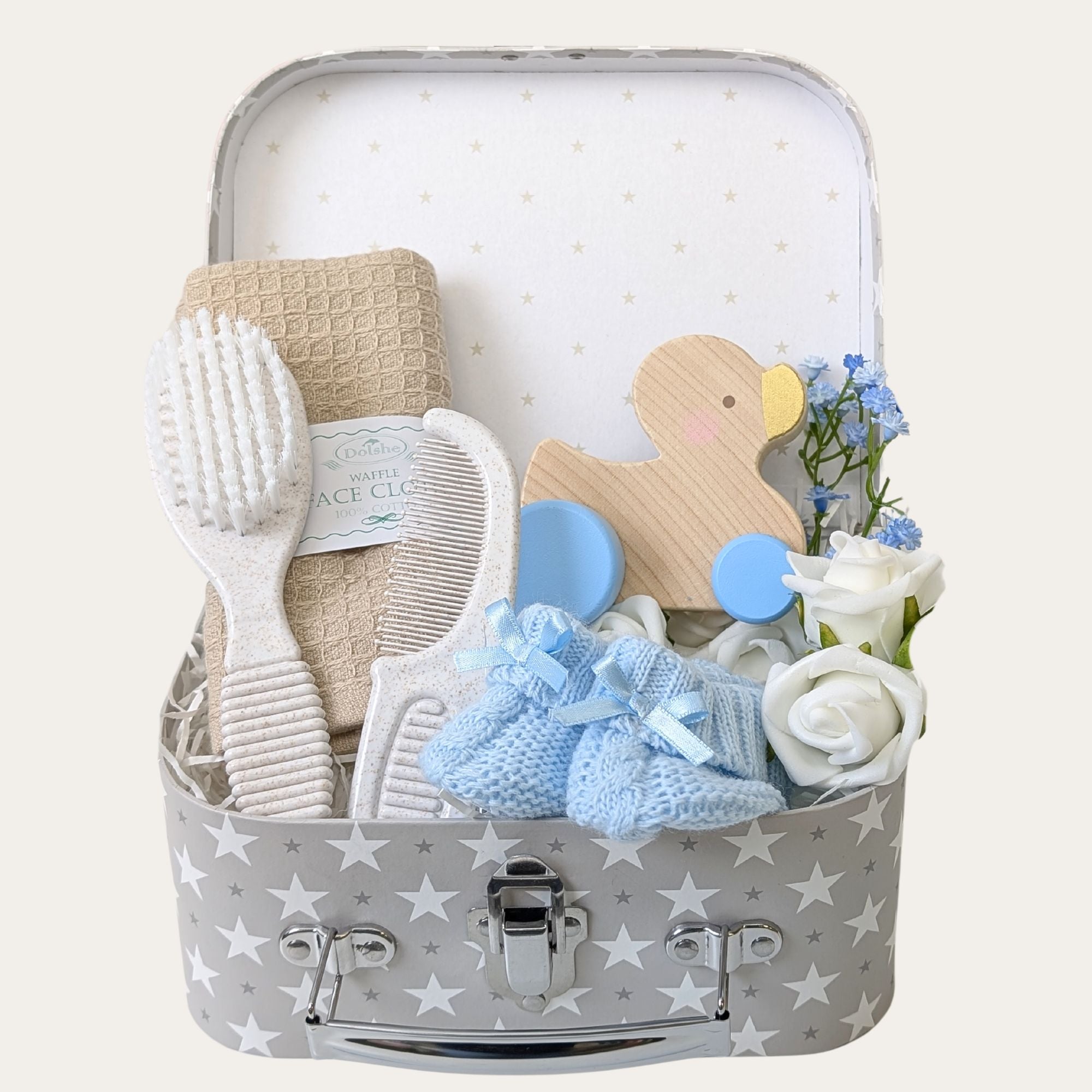 Eco-friendly baby boy gift set with soft cotton flannel, knit booties, brush and comb set, sensory toy duck, and keepsake luggage trunk. Perfect for gifting.