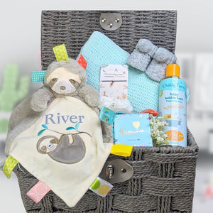 Personalised baby boy gifts basket with sloth blankie, mint green blanket, baby wash and treat for the parents.