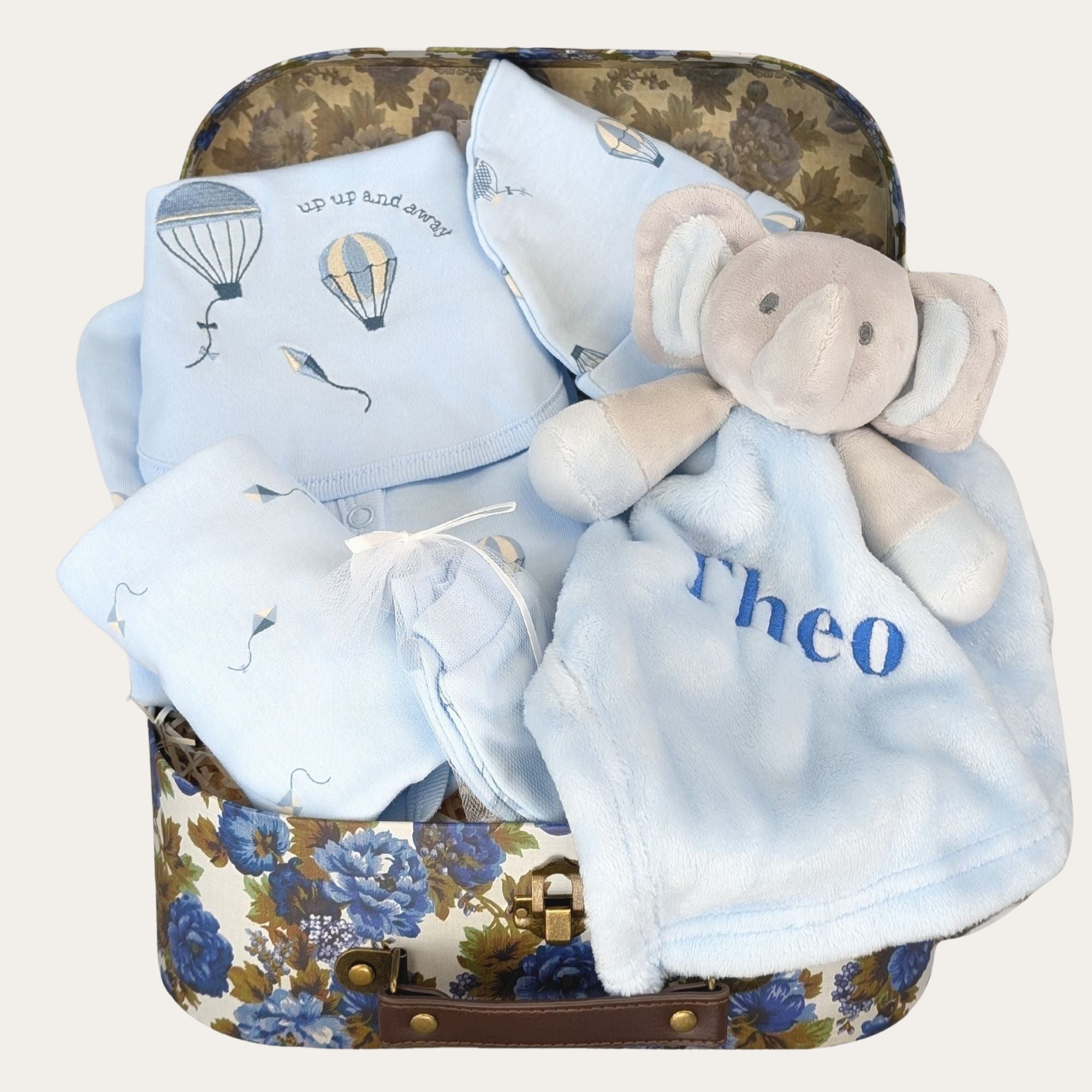 Baby boy hamper with gifts including a blue balloon clothes set and a personalised elephant comforter soft toy.