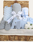 Gifts for a new baby boy in a hamper basket with grey and blue presents includes elephant rattle.