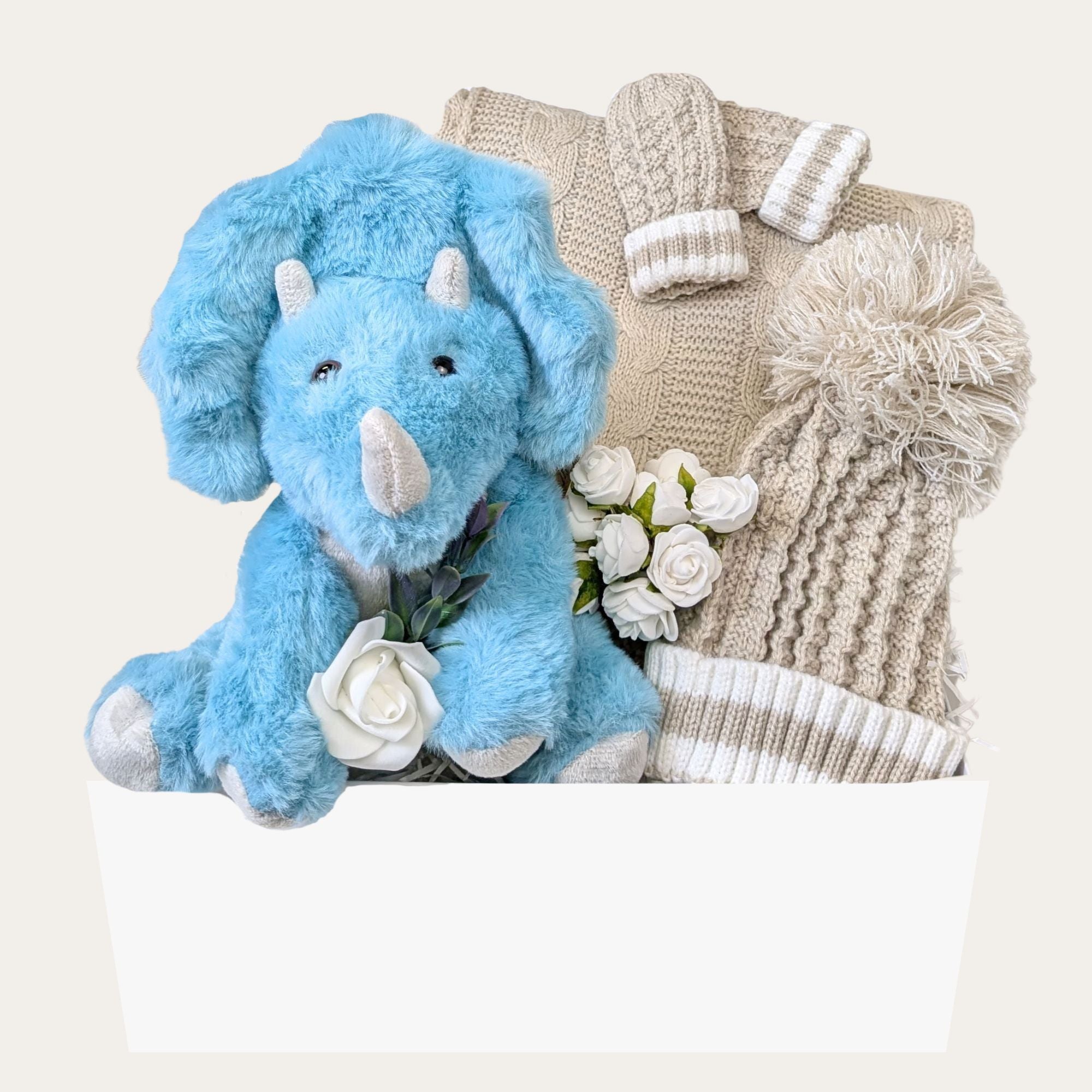 Eco-Friendly Baby Boy Gift Hamper with a recycled plush dinosaur, cosy knit hat, mittens, and a biscuit-toned cable knit blanket with pompoms, beautifully presented in a magnetic keepsake box.