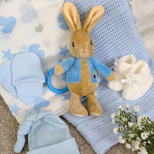 Peter Rabbit attachable toy on a background of blue cellular blanket and muslin cloth.