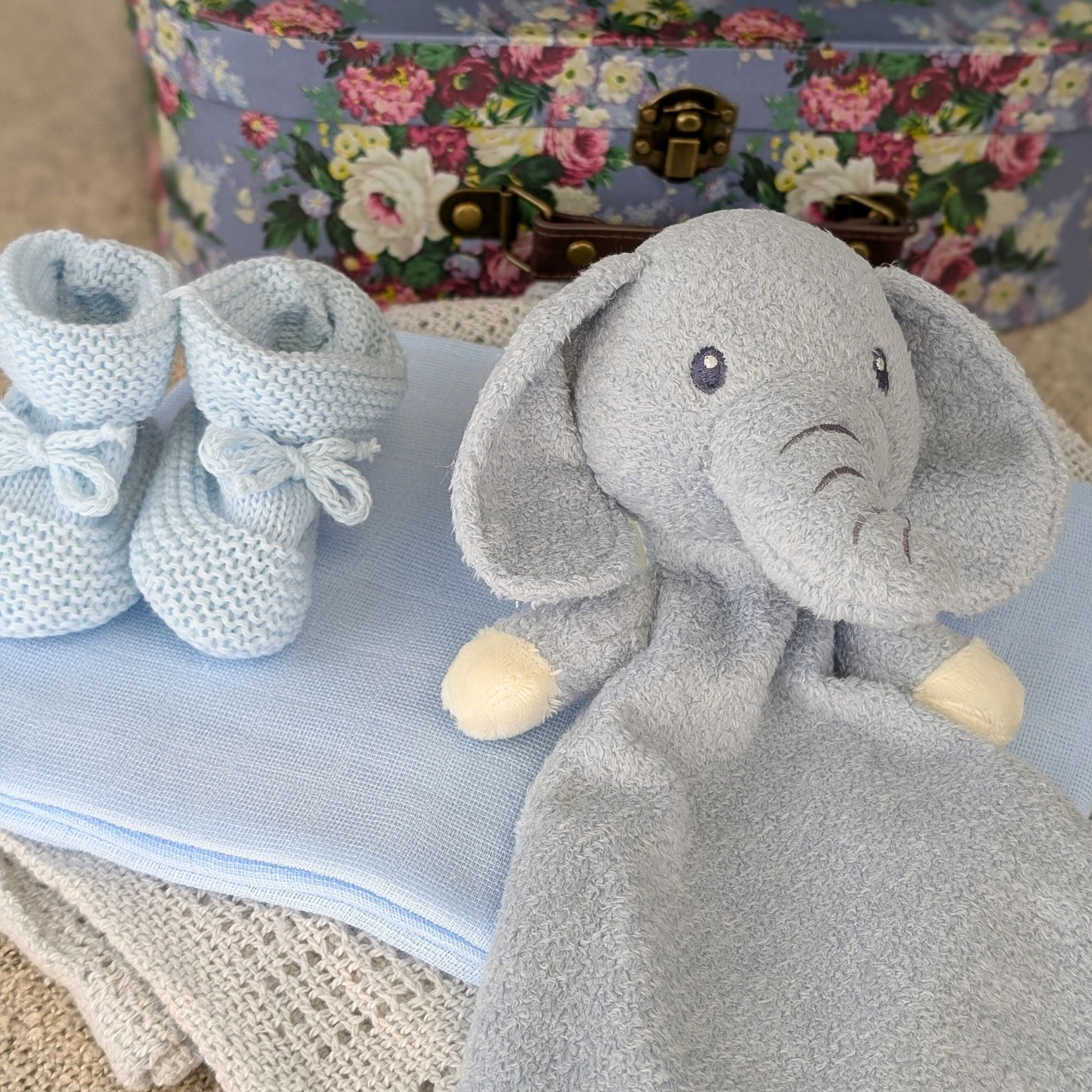 baby gifts hamper in blue with grey blanket, blue bib, blue booties, scratch mittens and elephant comforter blanket.