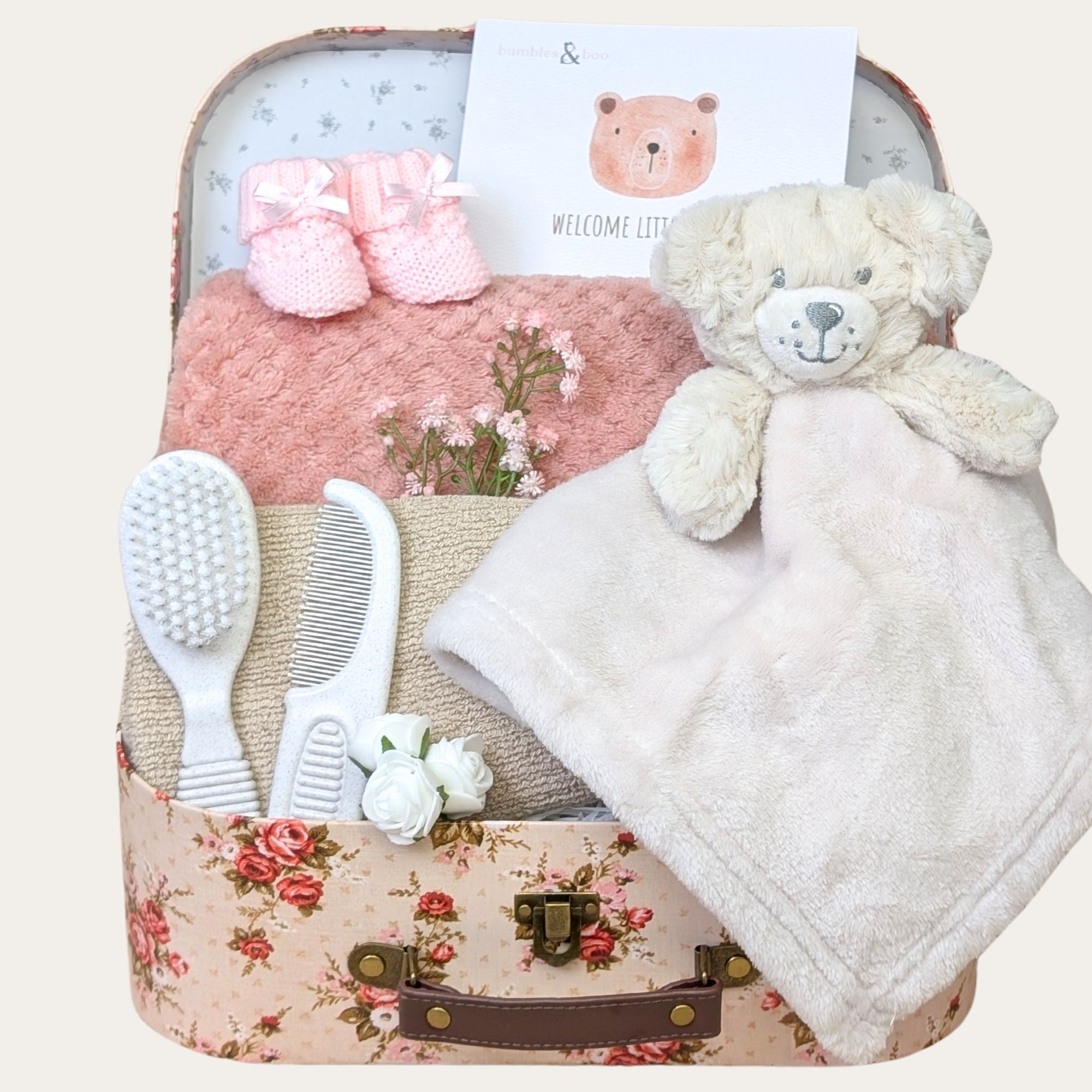 A charming baby girl gift hamper featuring soft knit booties, a personalised waffle blanket, an eco-friendly brush set, a cotton washcloth & a snuggly comforter toy. The perfect newborn gift! bumbles and boo.