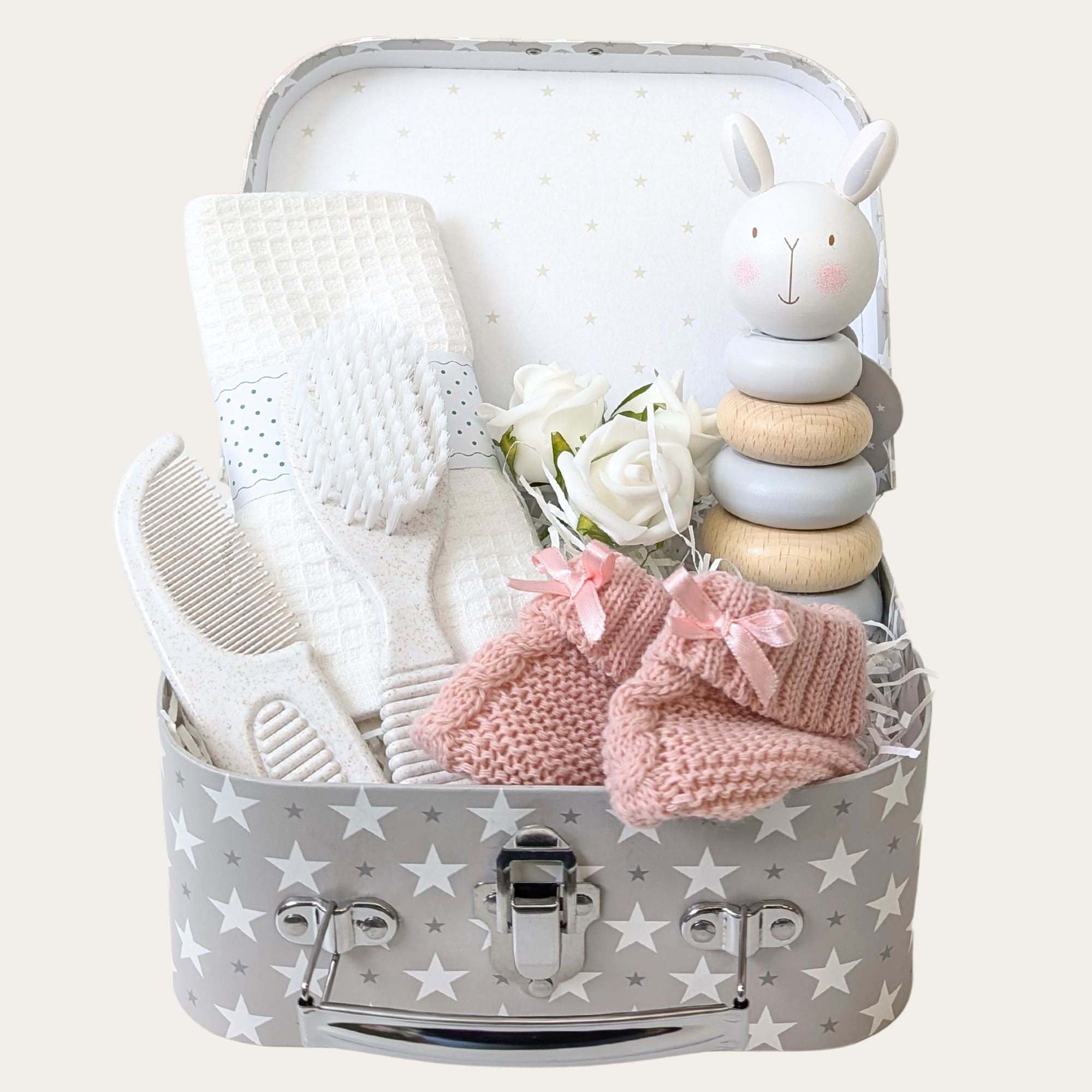 Eco-friendly baby girl gift set with a soft cotton flannel, pink knit booties, sustainable brush and comb set, wooden stacking toy, and a keepsake luggage trunk. Perfect for gifting.