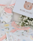 New baby girl clothing gifts hamper with a five piece rainbow themed clothing set and grey organic kitten soft toy. Presented in a hamper bag.