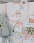 New baby girl clothing gifts hamper with a five piece rainbow themed clothing set and grey organic kitten soft toy. Presented in a hamper bag.