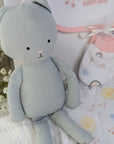 New baby girl clothing gifts hamper with a five piece rainbow themed clothing set and grey organic kitten soft toy. Presented in a hamper bag.