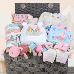 New baby girl gifts in a large hamper basket with pink striped baby clothes and blanket. Caterpillar themed baby toys and chocolate gifts for mummy.