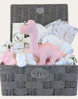 Baby girl gifts including organic pink dinosaur, cellular baby blanket and milestone cards in a dark brown hamper basket.