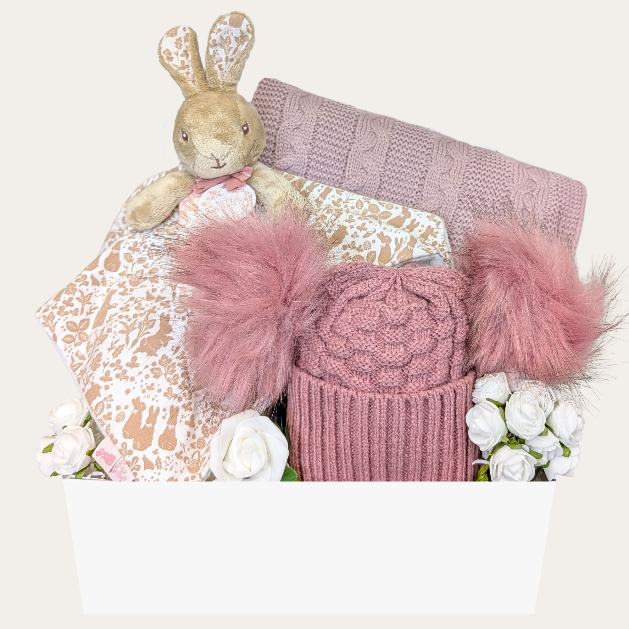 Baby girl gift hamper with a personalised Flopsy Bunny Comforter, dusky pink knit blanket, pompom hat, and greetings card. Perfect for a new arrival.