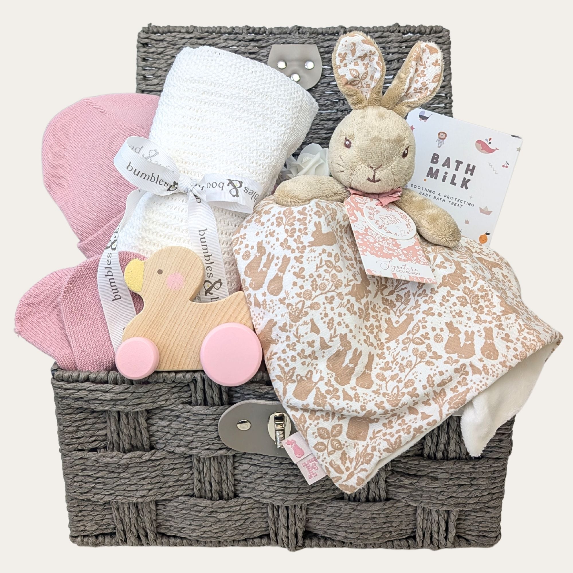 Baby girl gifts in a hamper basket with rabbit baby comforter and white blanket.