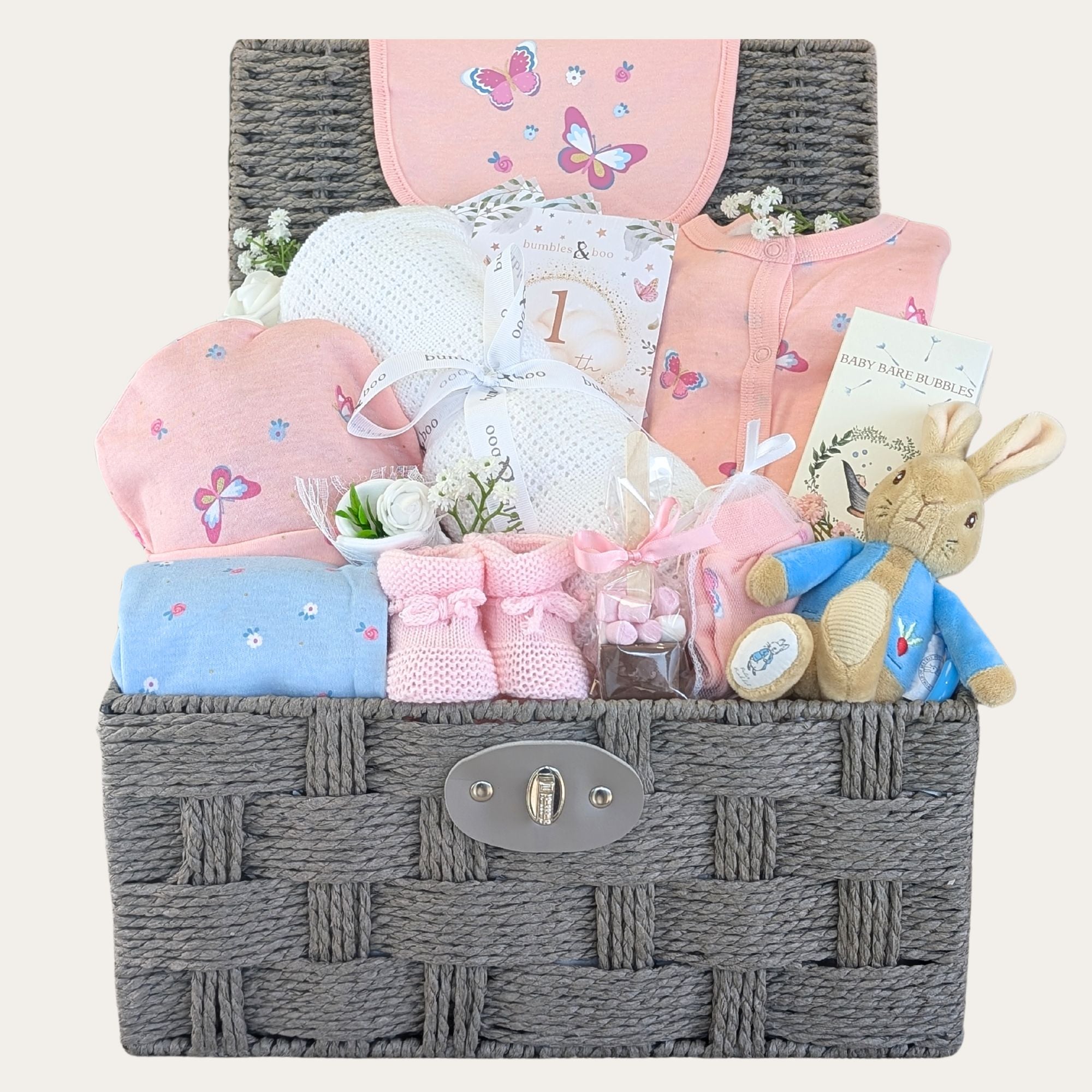 Gifts for baby girl in a hamper with pink newborn clothing set, peter rabbit soft toy.