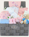 Gifts for baby girl in a hamper with pink newborn clothing set, peter rabbit soft toy.