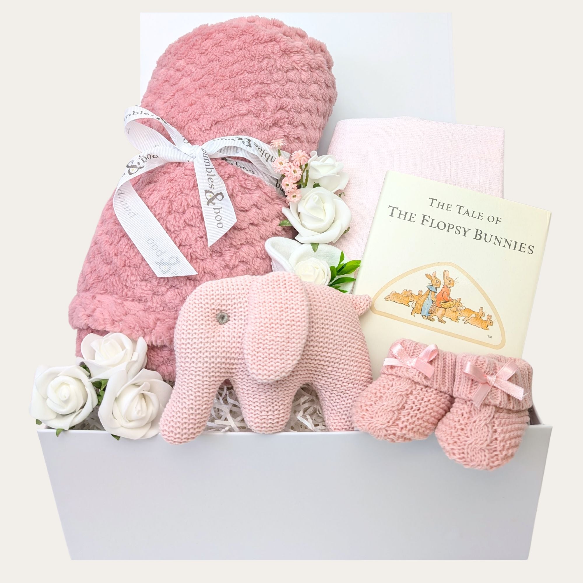 Baby girl gifts in a box with dusky pink blanket and pink elephant rattle.