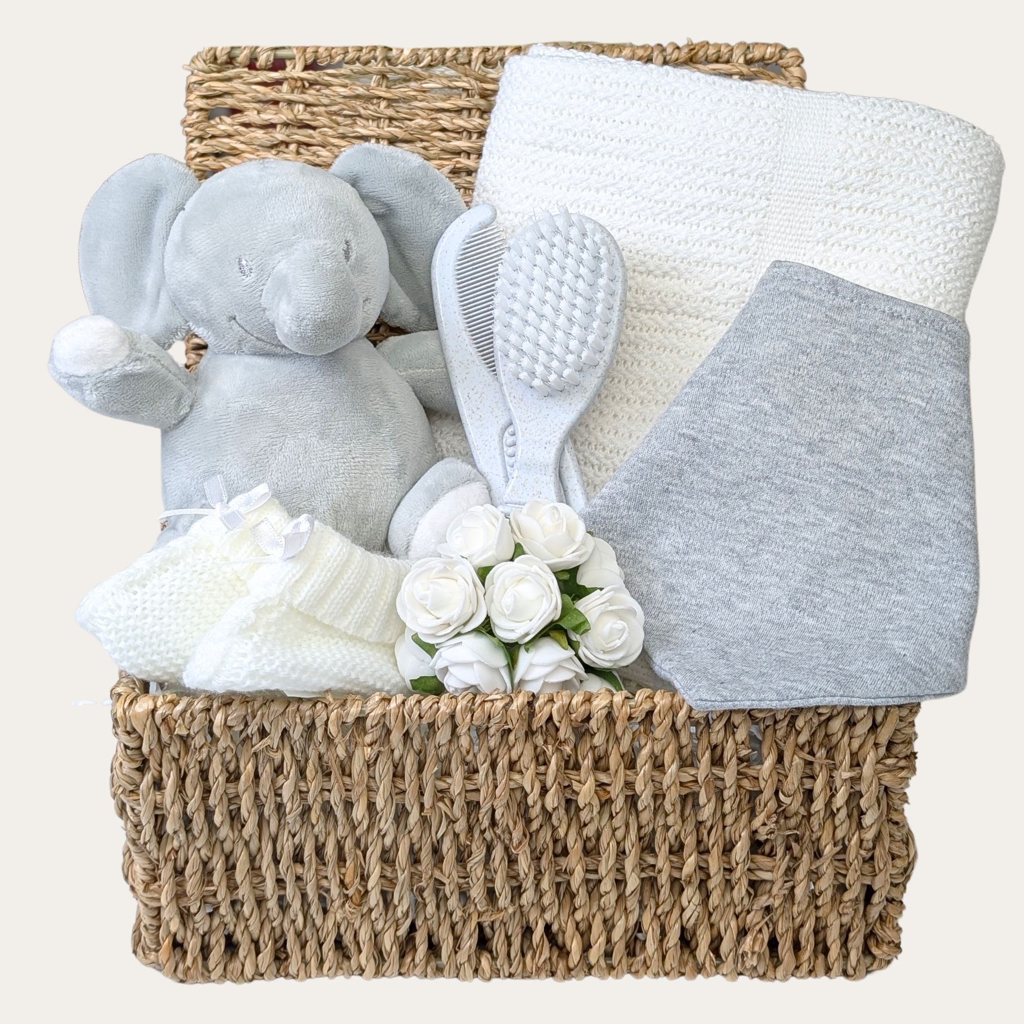 Adorable token gift set for a new mum or mum-to-be, including a soft elephant toy, white cellular baby blanket, grey cotton bandana bib, white knit mittens, and a sustainable brush and comb set.