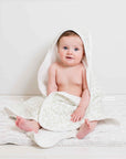 Soft white hooded baby bath towel with a green leaf print