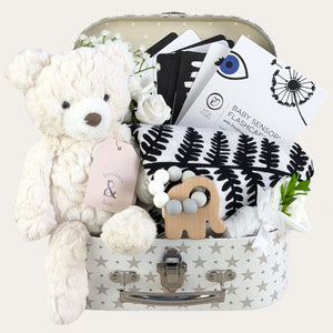 Baby hamper with  gifts of a white teddy bear and black and white muslin and sensory flash cards.