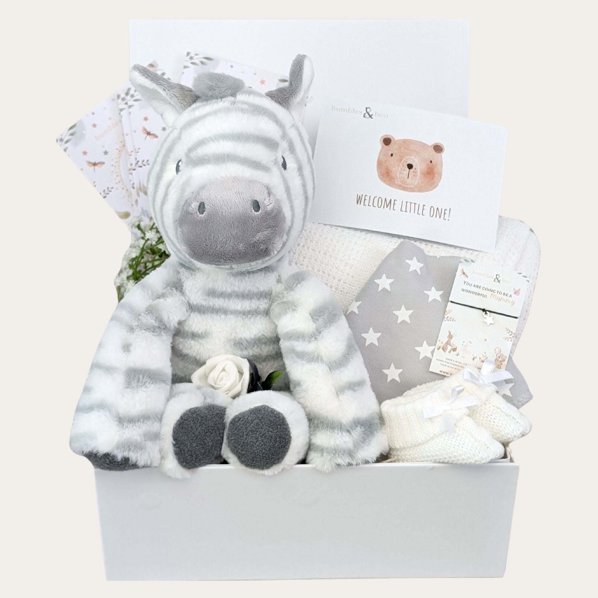 Baby shower hamper in a white gifts box with presents including  zebra soft toy, blanket and milestone cards.