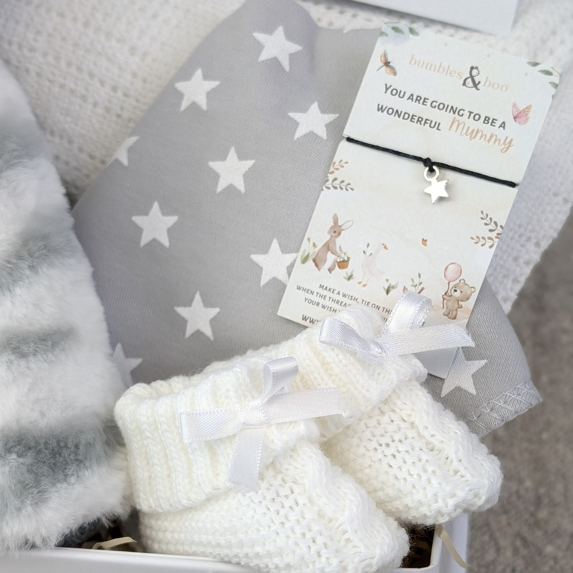 Right side of baby gift box with new mum bracelet and white booties.