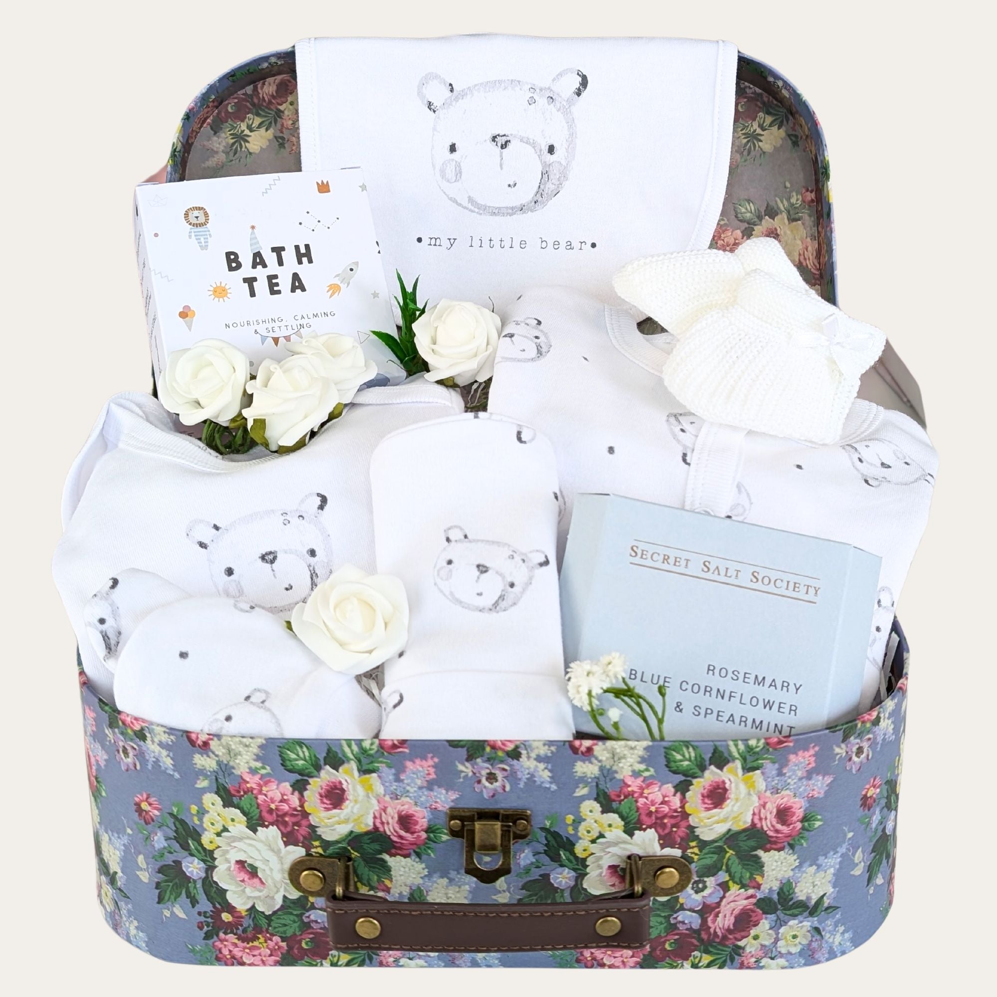 Baby shower gifts hamper with white baby clothes set decorated with a teddy pattern.