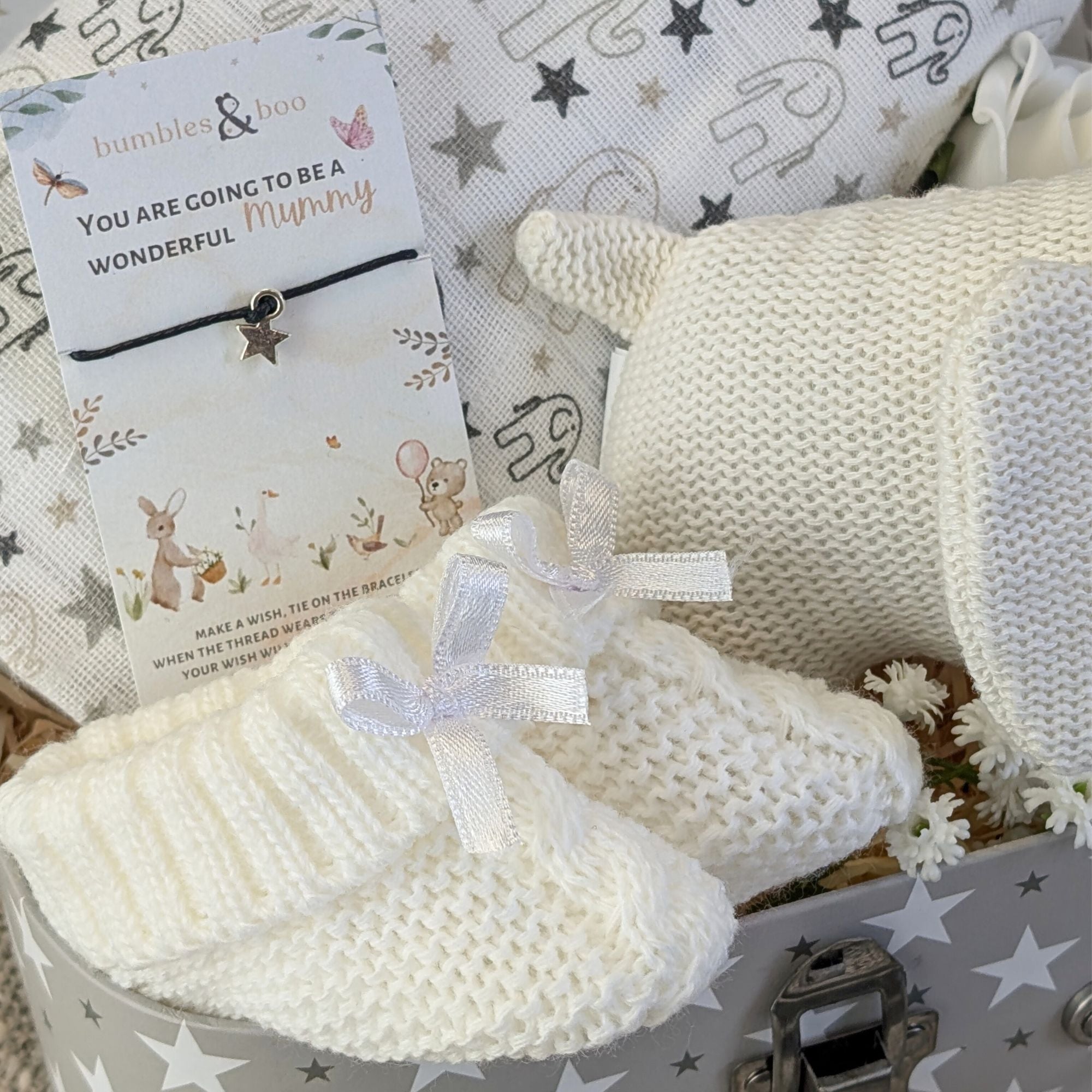 Close up of white baby booties and wish string.