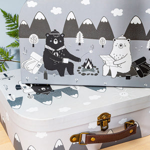 A set of two cardboard storage suitcase trunks in black, white and grey featuring two friendly bears on a camping adventure