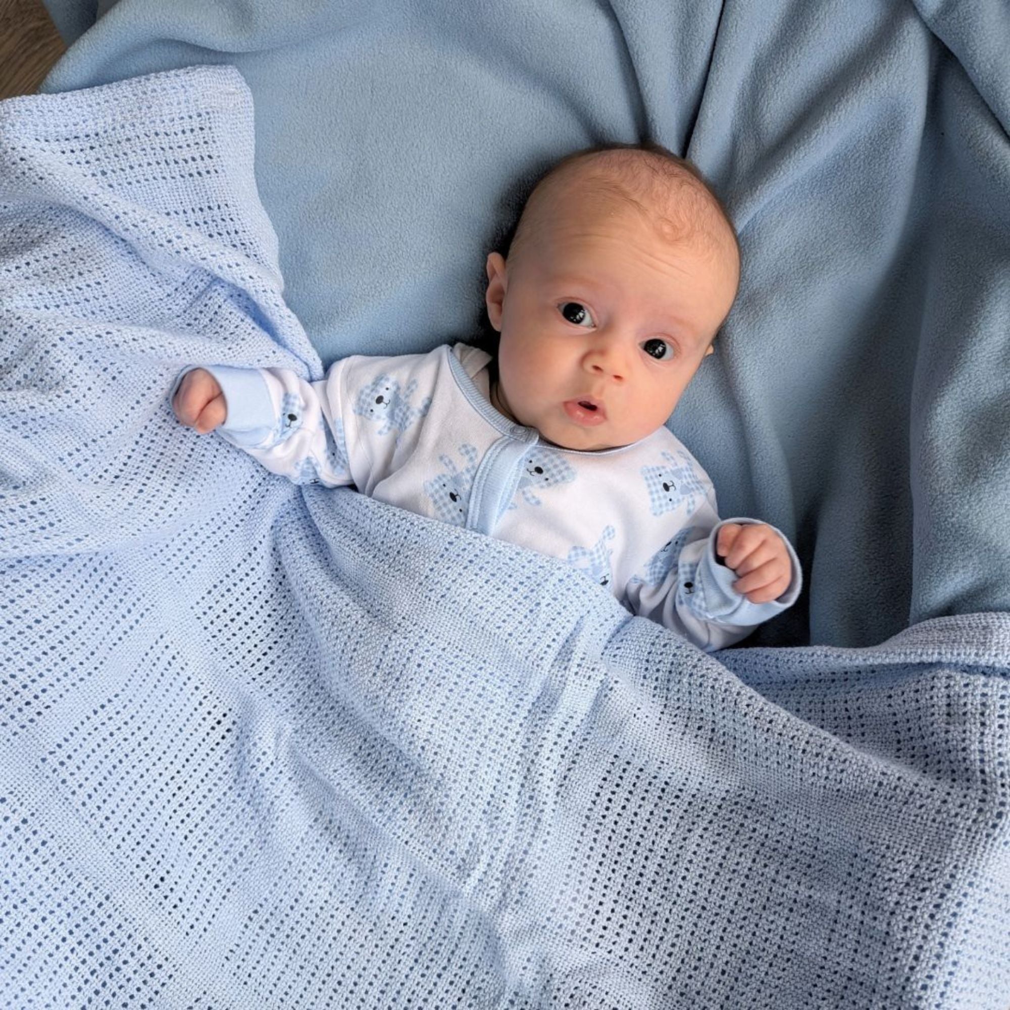 Blue cellular baby blanket covering a baby.