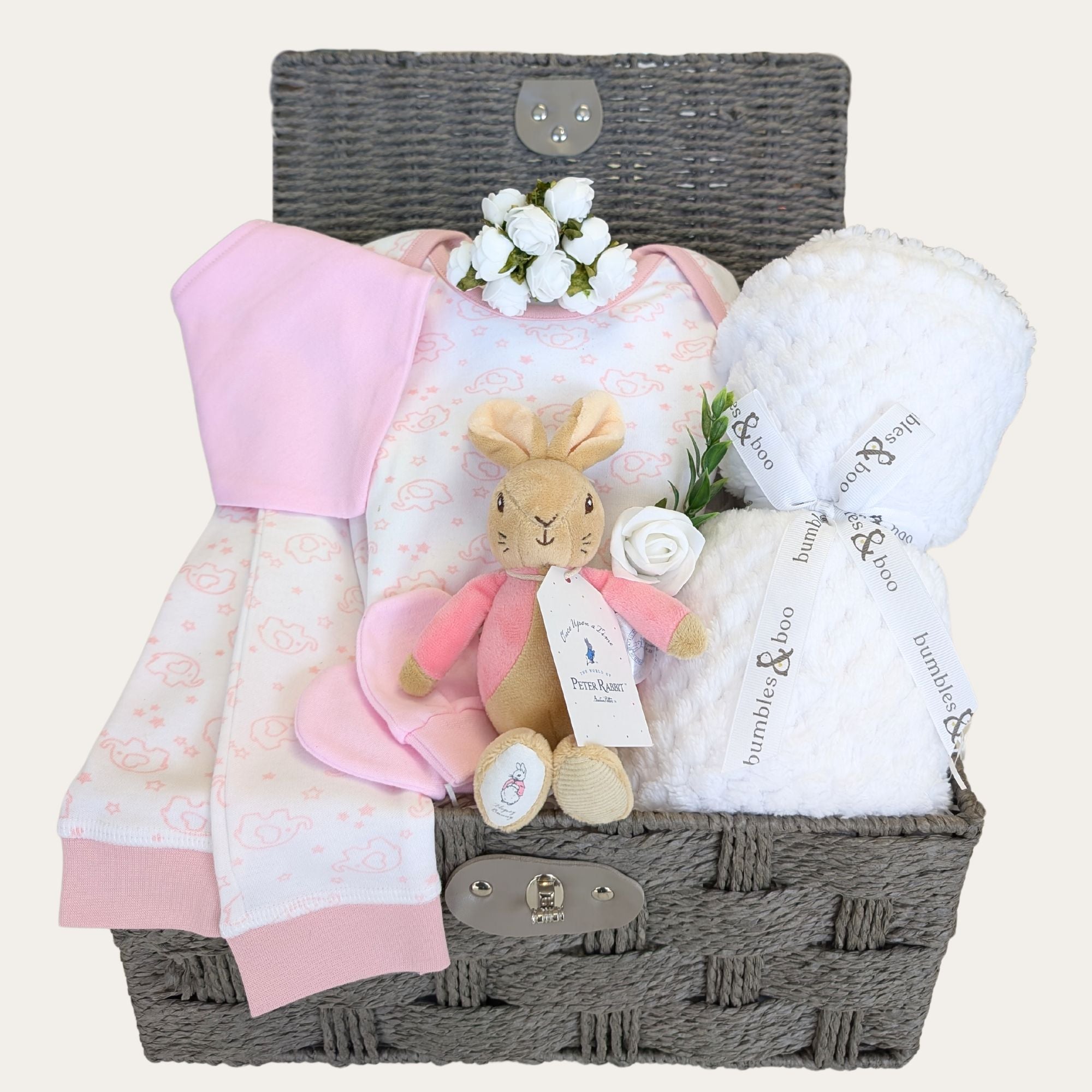 Baby girl hamper basket with gifts of pink pyjamas, white baby blanket, and bunny soft toy. 