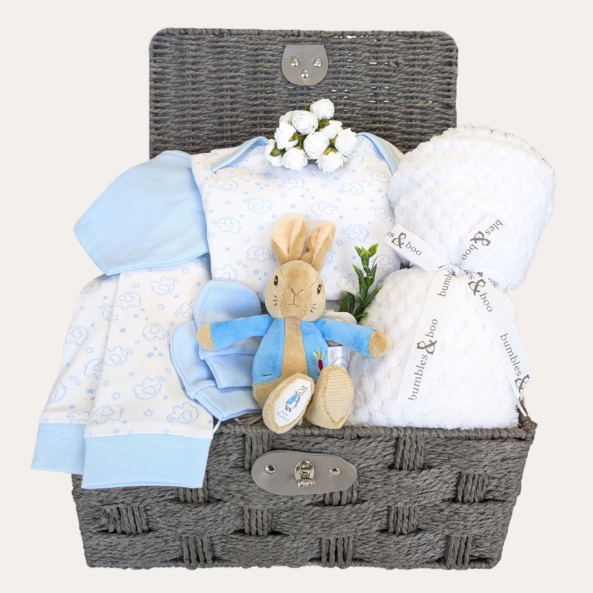 Baby boys gifts in a hamper basket with white blanket, bandana bib, pyjamas and peter rabbit soft toy.