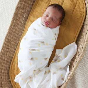 Two cotton muslin baby swaddles with chick designs, folded neatly on a surface.