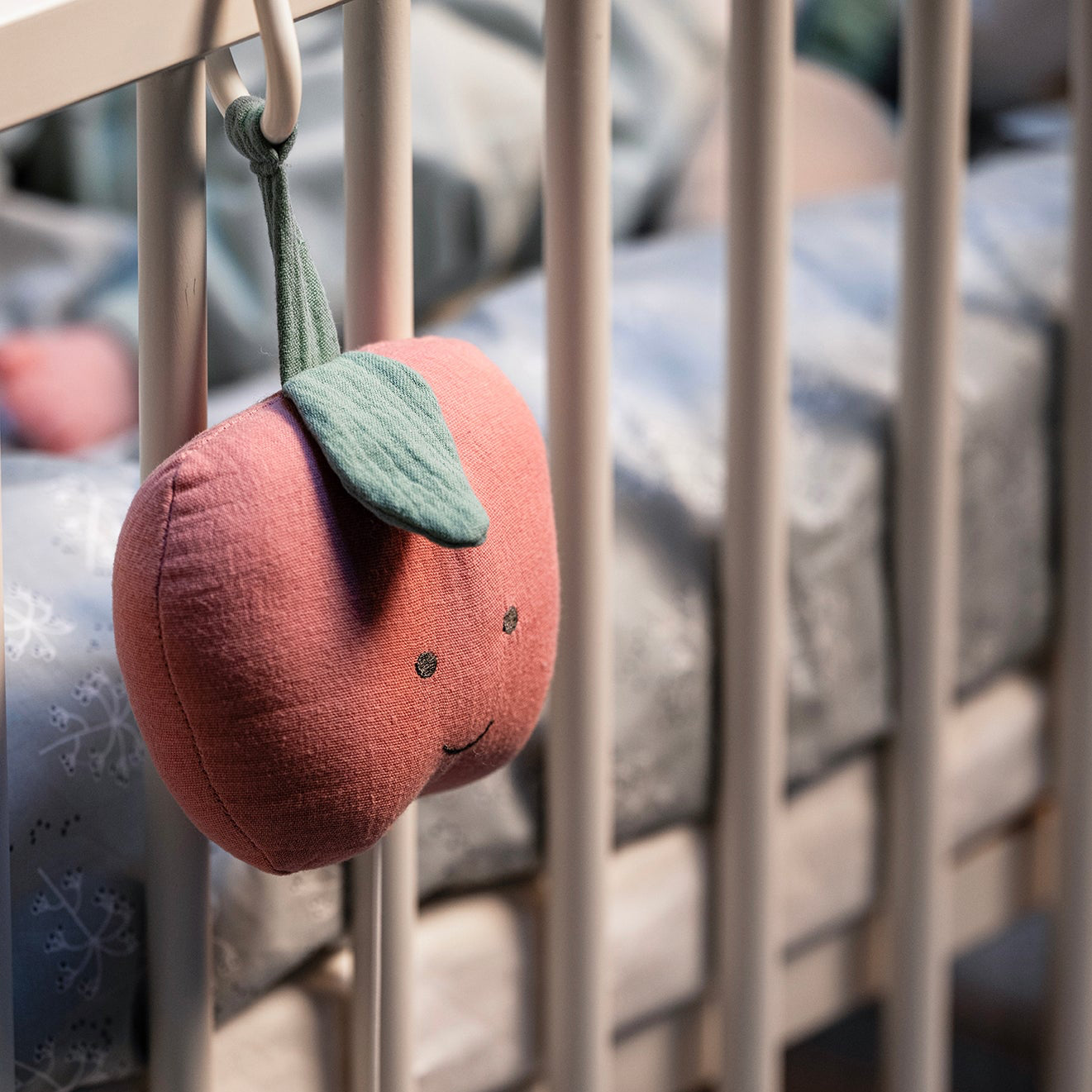 Baby cot featuring the Apple Musical Pull Toy.