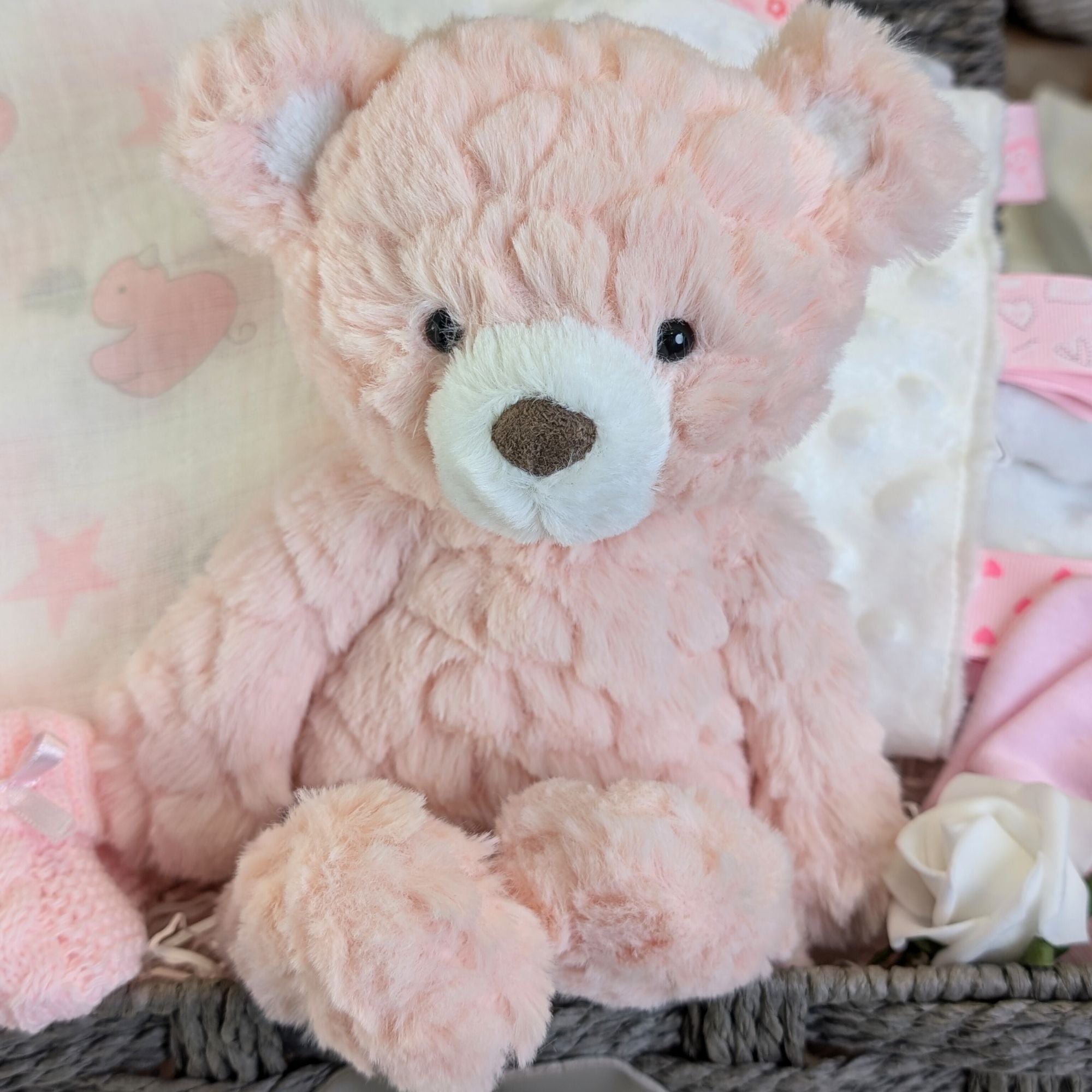 close up of a pink teddy bear in a new baby girl gifts hamper