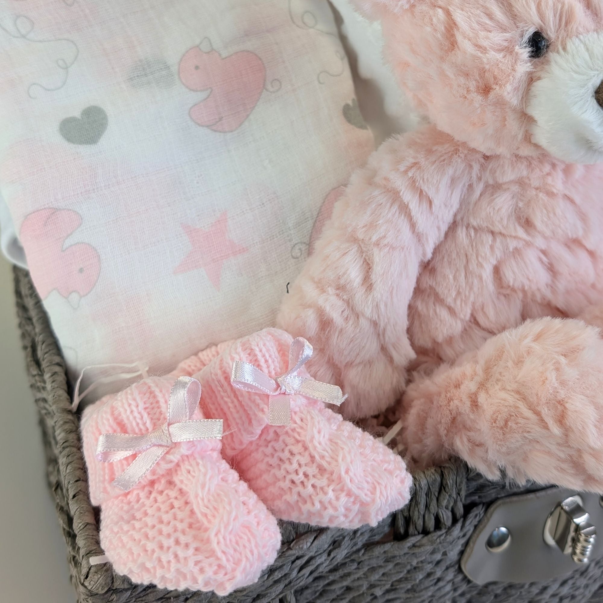 pink baby booties in a new baby girl gifts hamper with muslin and teddy