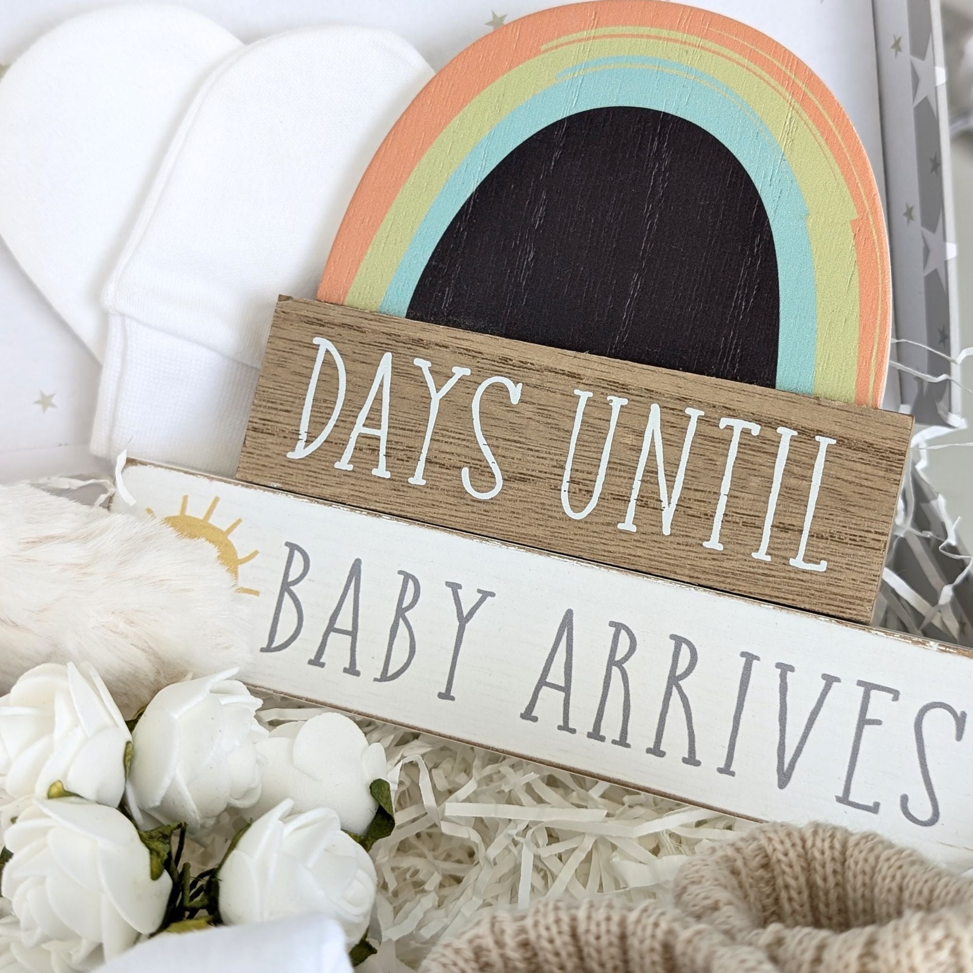 Close up of rainbow nursery plaque with writing saying 'Days until baby arrives' and chalkboard space for the countdown.