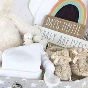 Close up of babu booties, white hat and nursery plaque.