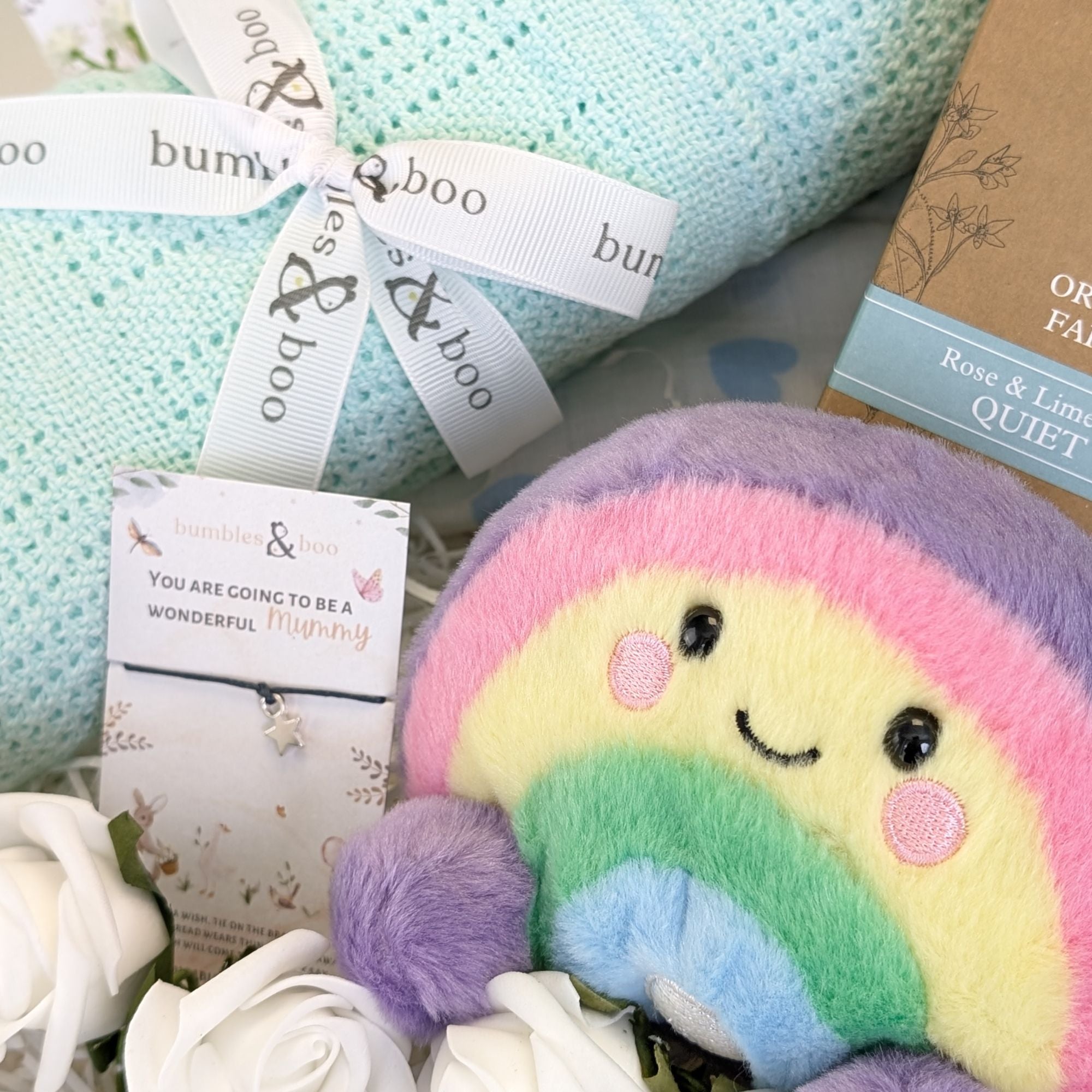 close up pregnancy gifts hamper with green blanket and rainbow soft toy