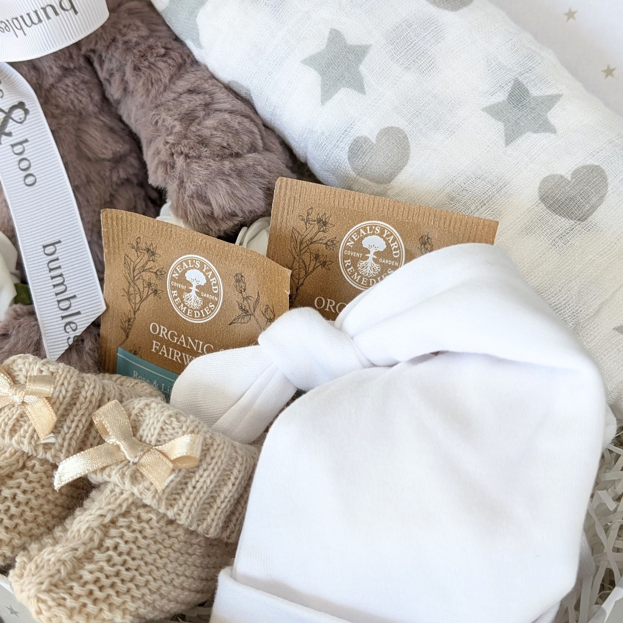 close up of a white baby har, baby organic tea, booties and cotton muslin