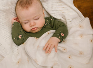 Large cotton muslin swaddle blanket with white design and daisy print flower design. 