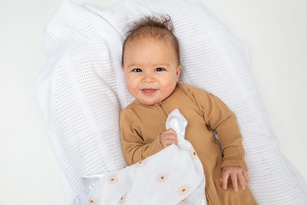 A white satin edged security blanket with a soft daisy print