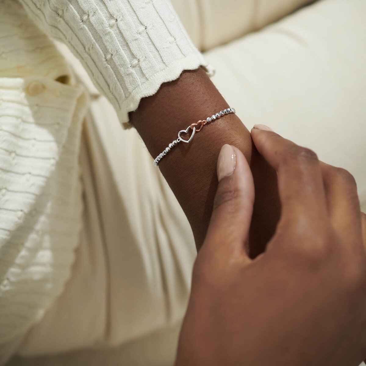 silver beaded bracelet with a silver and a rose gold heart