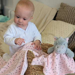 Pink hippo blanket and baby comforter set with a baby girl.