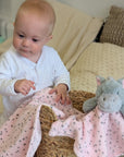 Pink hippo blanket and baby comforter set with a baby girl.