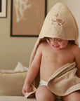 hooded organic baby bath towel biscuit colour on a baby with an embroidered deer