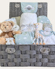 Baby shower gifts hamper with baby clothes set, teddy bear and teething toy in a basket .