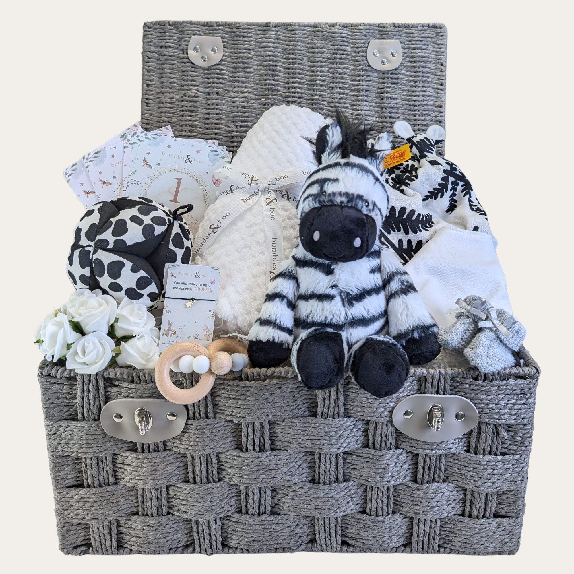 Baby gifts in a hamper basket with a black and white theme. Includes Zebra toy and baby blanket.