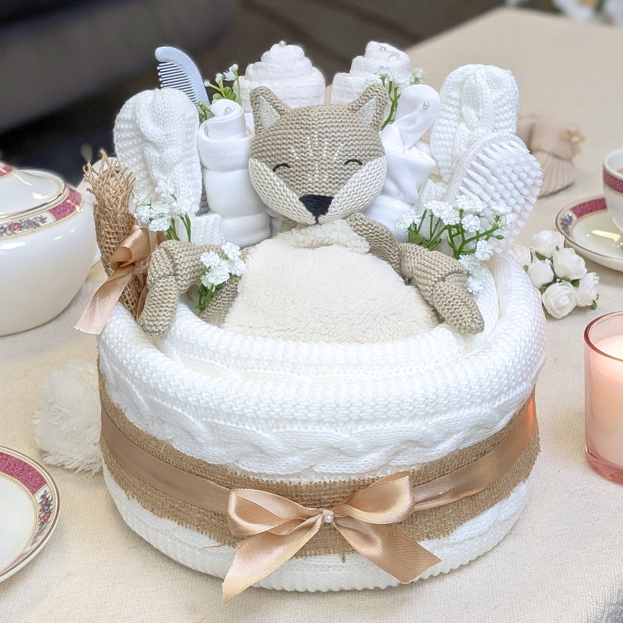 white baby nappy cake which includes a baby blanket, baby clothing, organic mr fox and brush and comb. bumbles and boo.